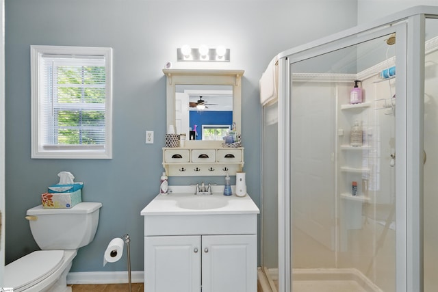 bathroom with toilet, vanity, ceiling fan, and a stall shower