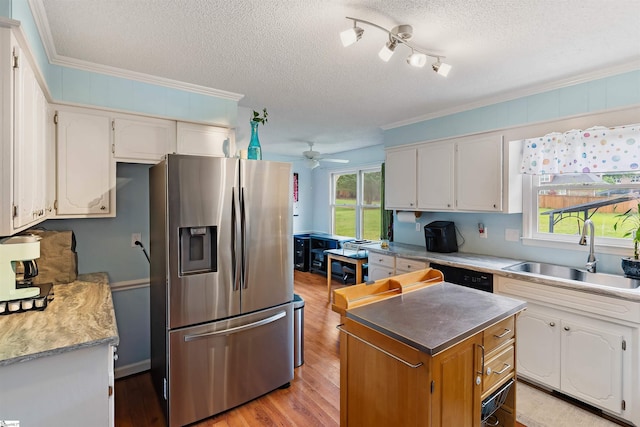kitchen with ornamental molding, a sink, stainless steel fridge, a textured ceiling, and white cabinetry