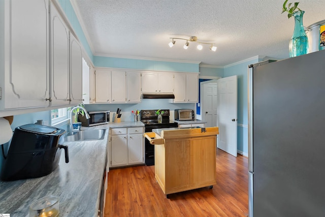 kitchen featuring white cabinetry, appliances with stainless steel finishes, light countertops, under cabinet range hood, and ornamental molding