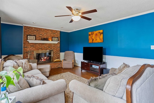 living area featuring a ceiling fan, wood finished floors, a textured ceiling, and crown molding