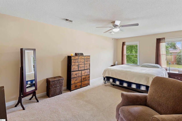 bedroom with a textured ceiling, carpet, visible vents, and baseboards