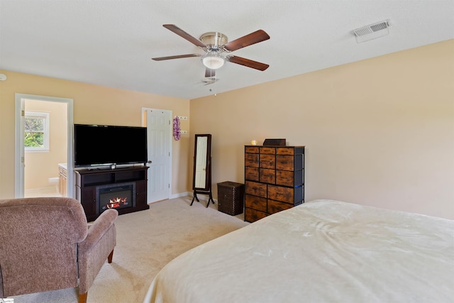 carpeted bedroom with ceiling fan, baseboards, a glass covered fireplace, and visible vents
