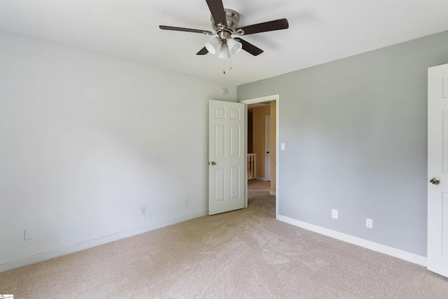 empty room with ceiling fan, light carpet, and baseboards