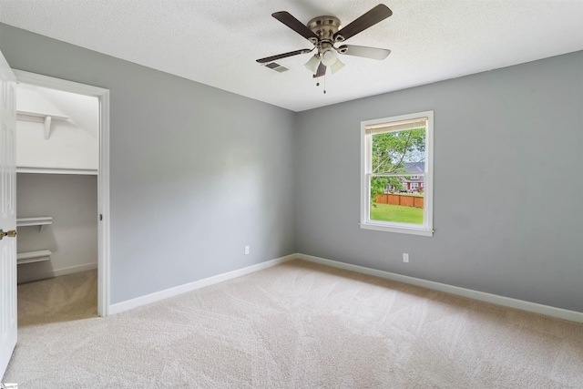 unfurnished bedroom featuring a walk in closet, visible vents, carpet flooring, and baseboards