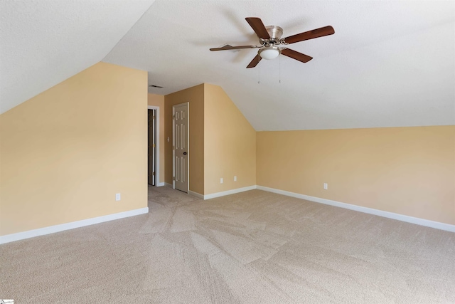 bonus room with baseboards, vaulted ceiling, light colored carpet, and a ceiling fan