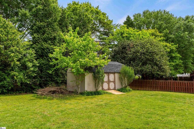 view of yard featuring a storage shed, fence, and an outdoor structure