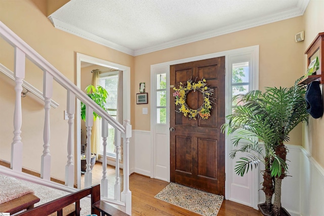 foyer featuring wood finished floors, a wealth of natural light, a textured ceiling, and stairway
