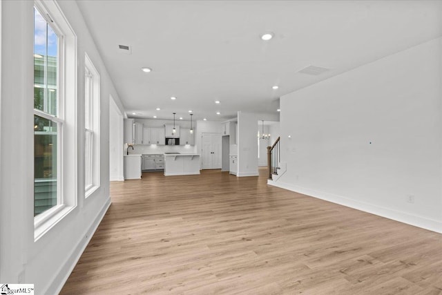 407 Briggs Dr, Easley, SC 29642 - unfurnished living room with stairway, recessed lighting, light wood-style flooring, and a sink