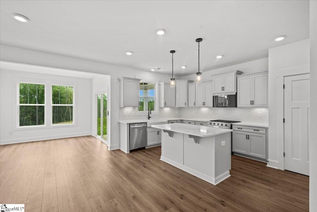407 Briggs Dr, Easley, SC 29642 - kitchen with appliances with stainless steel finishes, light countertops, a kitchen island, backsplash, and dark wood-type flooring