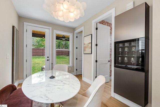 dining space with baseboards, a notable chandelier, french doors, and light wood-style floors