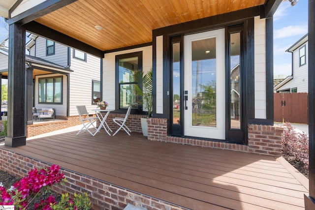 wooden terrace featuring a porch and fence