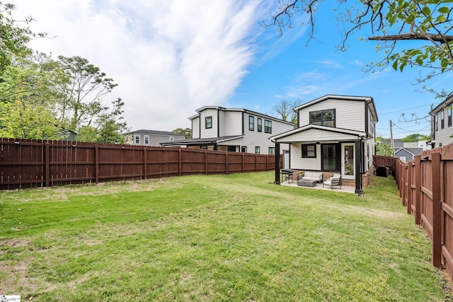 rear view of property with a lawn, a patio, and a fenced backyard