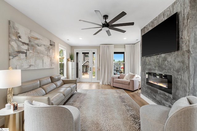 living area featuring a premium fireplace, wood finished floors, recessed lighting, and ceiling fan