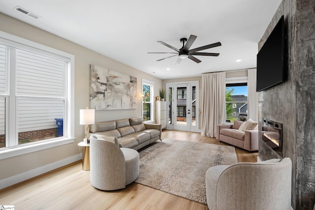 living room with light wood-style flooring, visible vents, ceiling fan, and a healthy amount of sunlight