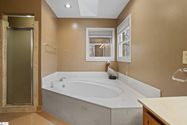 full bathroom featuring a garden tub, vanity, and a stall shower
