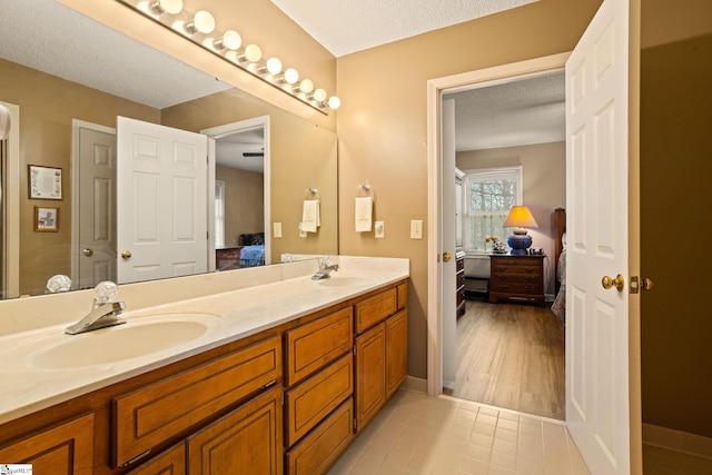 bathroom featuring connected bathroom, a sink, double vanity, and a textured ceiling