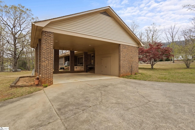 exterior space featuring driveway, brick siding, and a yard