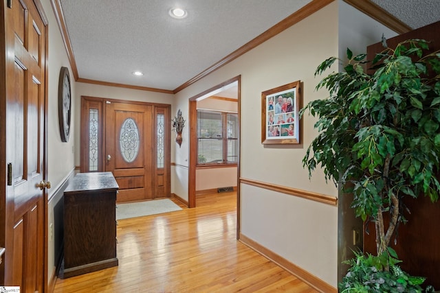 foyer entrance featuring baseboards, crown molding, a textured ceiling, and light wood-style floors