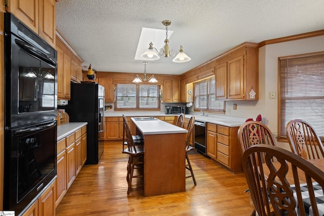kitchen featuring light countertops, light wood-type flooring, black appliances, a textured ceiling, and a notable chandelier