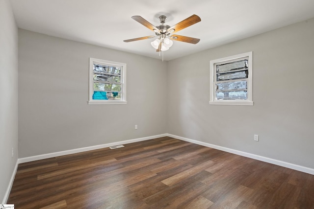 unfurnished room with dark wood finished floors, visible vents, baseboards, and ceiling fan