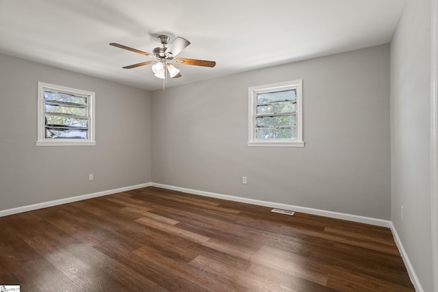 unfurnished room featuring baseboards, plenty of natural light, visible vents, and dark wood-style floors