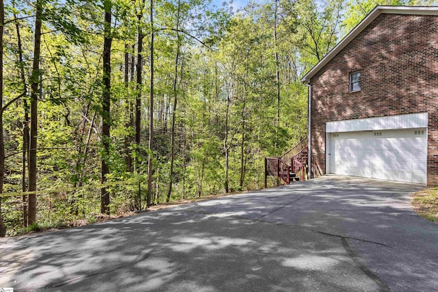 112 Jocassee Falls Rd, Salem, SC 29676 - view of side of home with stairway, a wooded view, aphalt driveway, an attached garage, and brick siding
