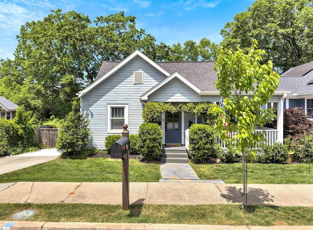 bungalow-style home with fence, a shingled roof, a front lawn, and a porch