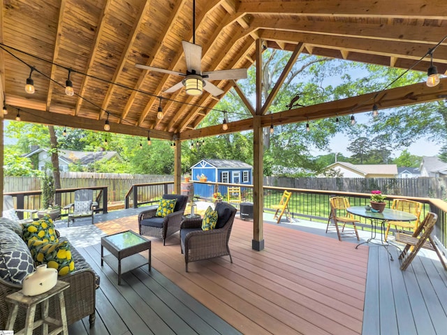 wooden terrace with a fenced backyard, outdoor lounge area, a shed, and ceiling fan
