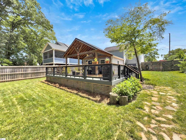 rear view of house featuring a yard, a sunroom, a fenced backyard, and a deck