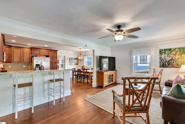 living area with dark wood-style floors, recessed lighting, ceiling fan, and crown molding