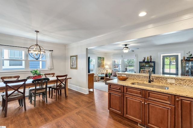 kitchen featuring decorative light fixtures, dark wood-style floors, light stone counters, and a sink
