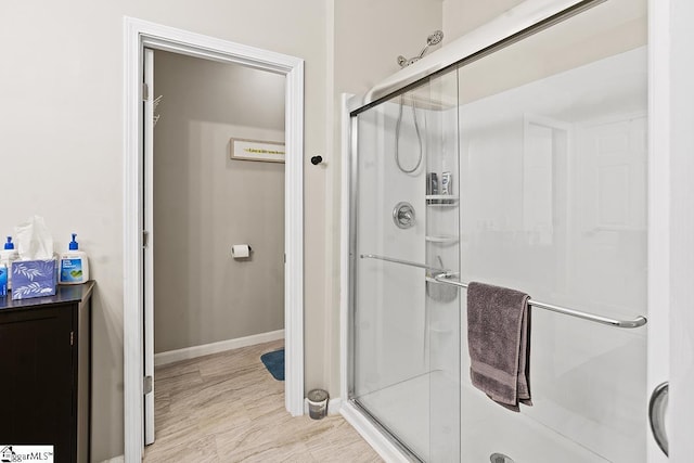 bathroom featuring baseboards, wood finished floors, and a stall shower