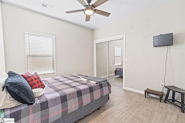 bedroom with light wood finished floors, baseboards, visible vents, a closet, and ceiling fan