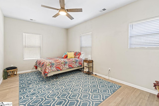 bedroom featuring baseboards, wood finished floors, visible vents, and a ceiling fan