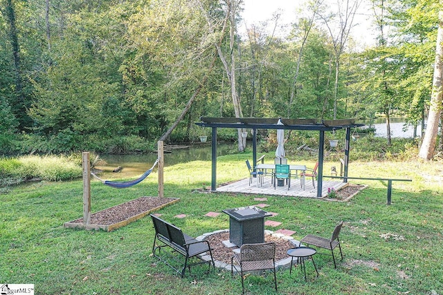 view of jungle gym with a patio area, a water view, a yard, and a wooded view