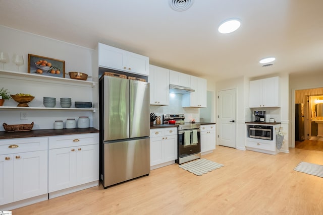 409 Freeman Bridge Rd, Marietta, SC 29661 - kitchen with appliances with stainless steel finishes, dark countertops, under cabinet range hood, light wood-style flooring, and open shelves