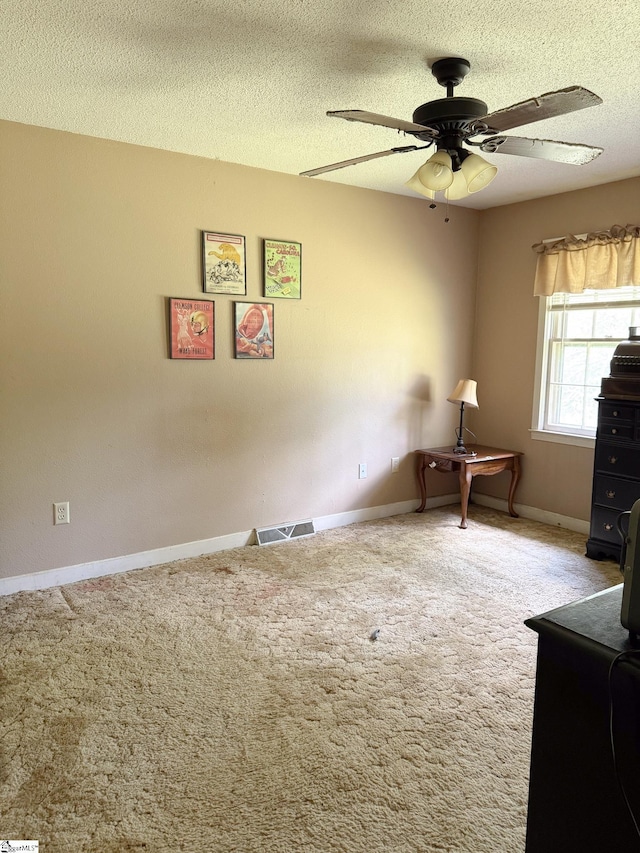 unfurnished office with a textured ceiling, ceiling fan, carpet floors, baseboards, and visible vents