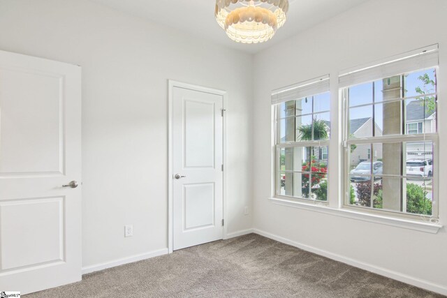 unfurnished bedroom with carpet floors, baseboards, multiple windows, and an inviting chandelier