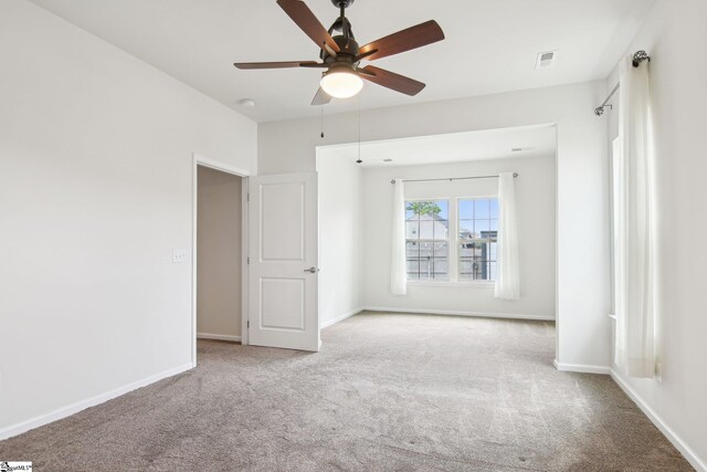 unfurnished room featuring visible vents, baseboards, a ceiling fan, and carpet flooring