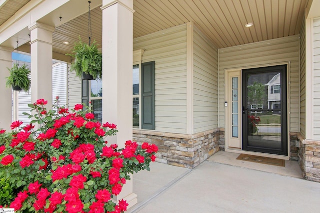 view of exterior entry featuring a porch and stone siding