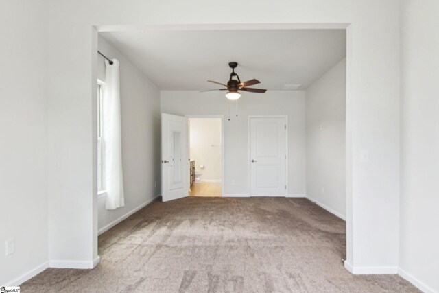 spare room featuring light carpet, baseboards, and ceiling fan