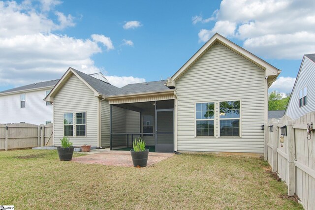 back of property with a gate, a fenced backyard, a yard, a patio, and a sunroom