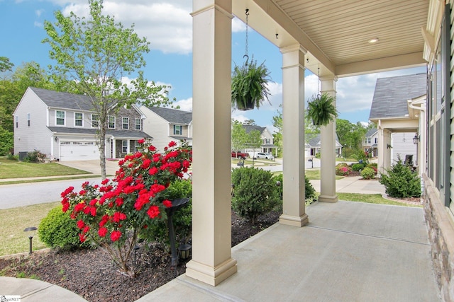 view of patio / terrace featuring a garage, a porch, and a residential view