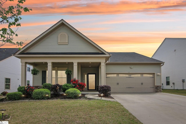 view of front of house with concrete driveway, a lawn, an attached garage, and covered porch