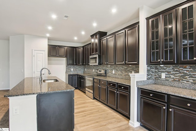 kitchen with stone countertops, a sink, appliances with stainless steel finishes, and tasteful backsplash