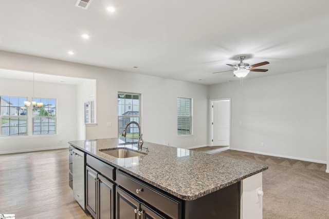 kitchen with recessed lighting, a sink, stone counters, open floor plan, and ceiling fan with notable chandelier