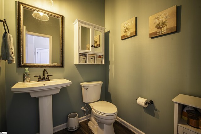 bathroom with toilet, wood finished floors, and baseboards