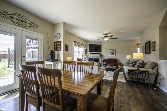 dining room featuring a ceiling fan, baseboards, a fireplace, and dark wood finished floors