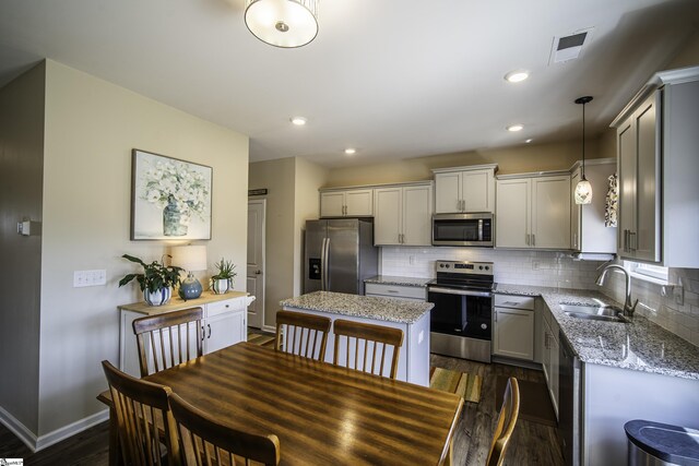 kitchen with decorative backsplash, stainless steel appliances, a sink, and dark wood-style flooring