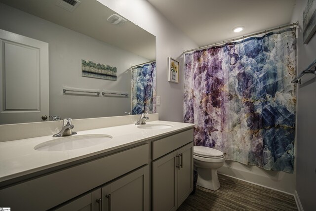 bathroom featuring double vanity, visible vents, toilet, and a sink